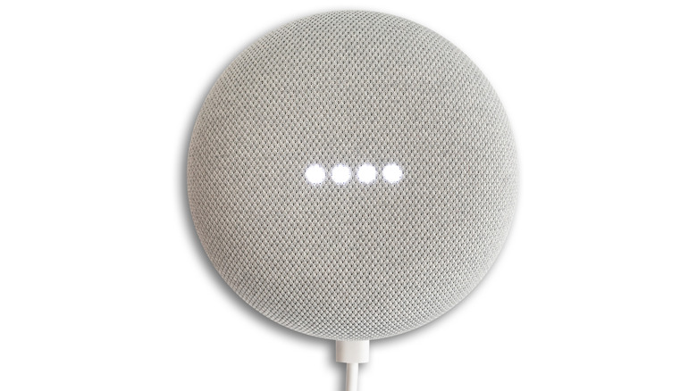 A Google Nest Mini speaker on a white background, with a cable attached to it