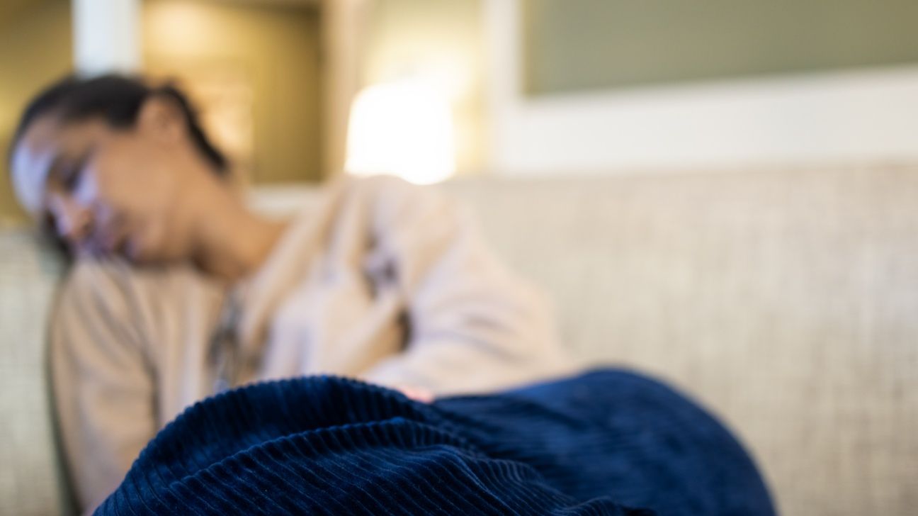 Blurred image of a female lying on a sofa holding her stomach