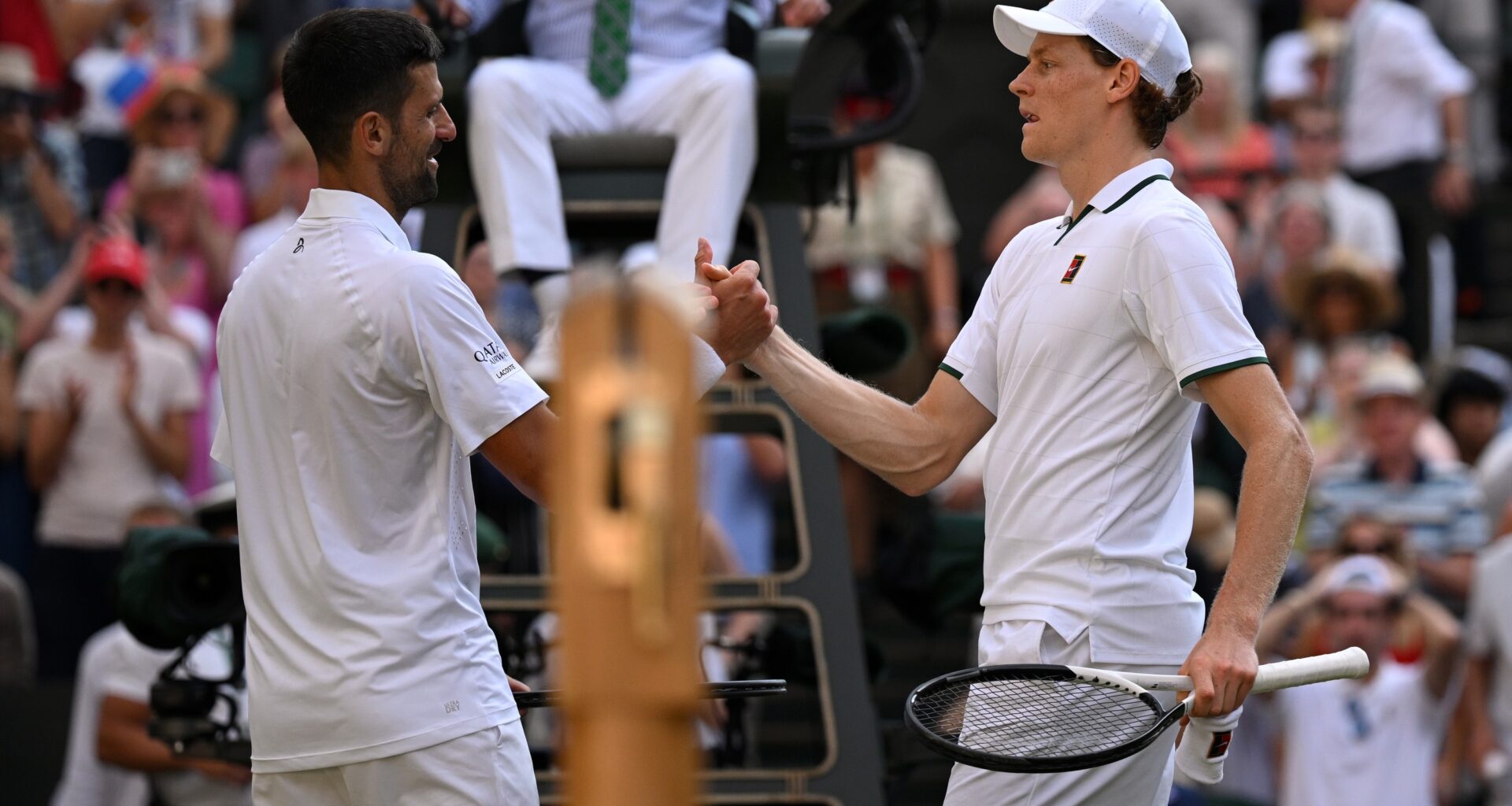 Two tennis players interact at the net.