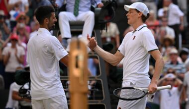 Two tennis players interact at the net.