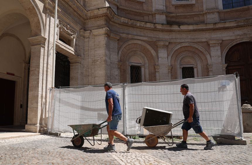 Construction workers carry air conditioning units in Rome on July 10.