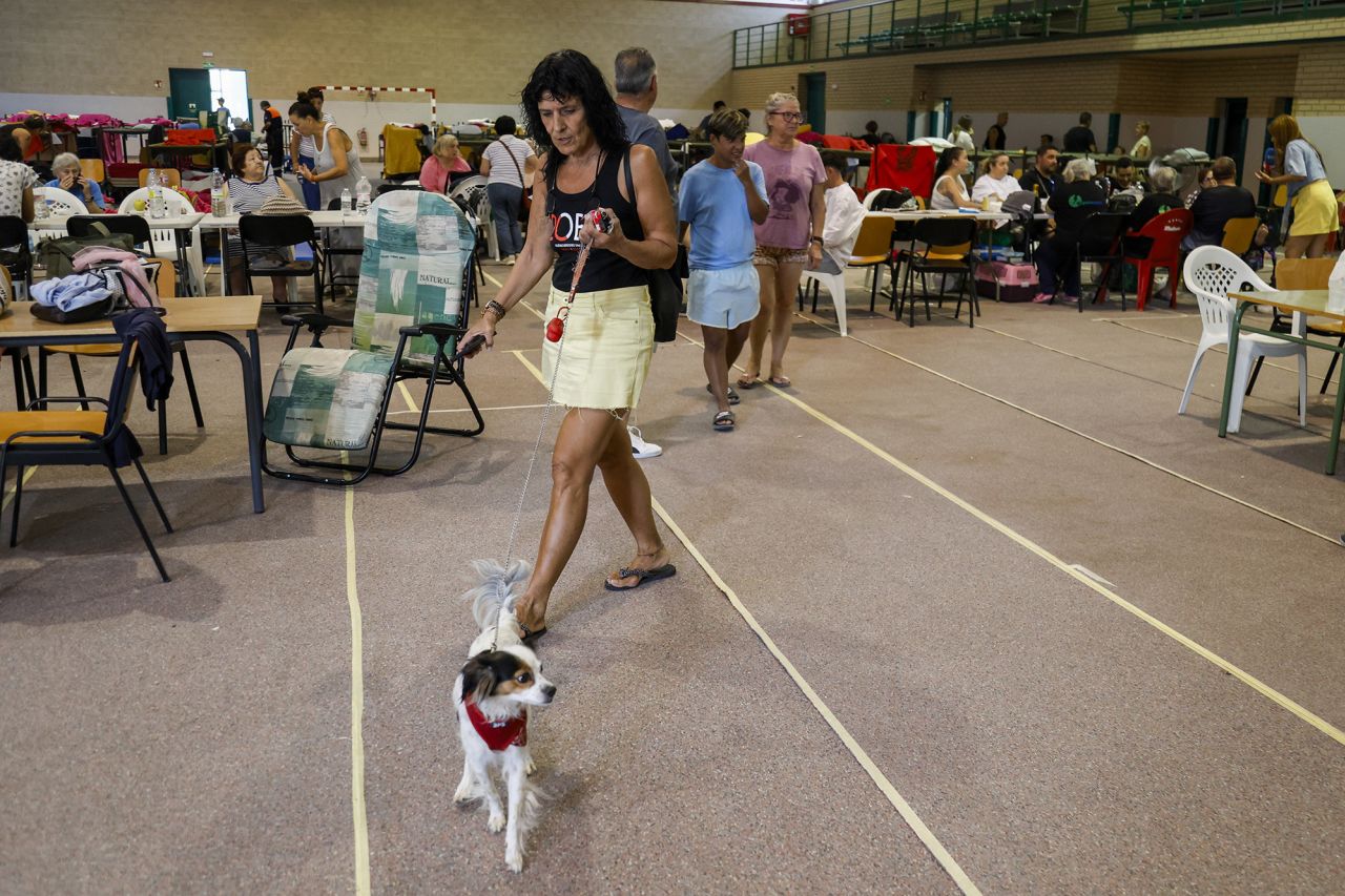 A woman walks her dog at a shelter for those evacuated due to the wildfires in Villamanta, Spain, on Monday.
