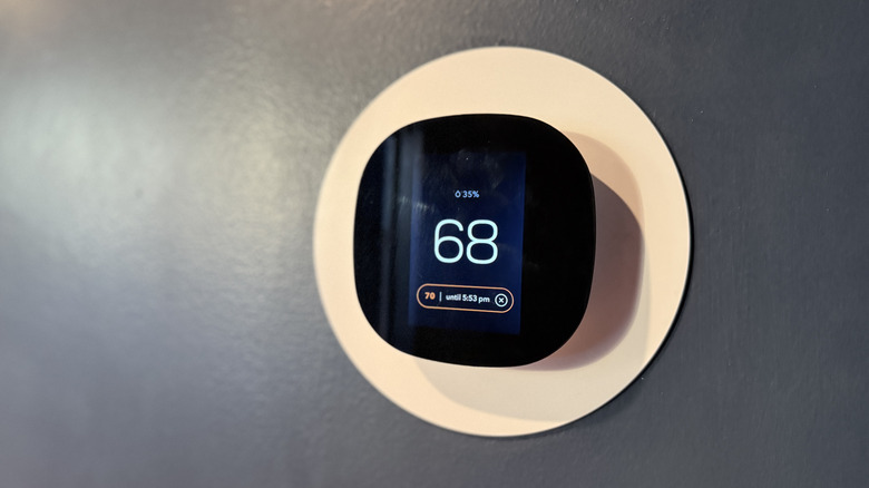A smart thermostat attached to the wall, showing the temperature