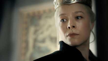 An image from House of the Dragon (HOTD) featuring Emma D'arcy as Rhaenyra Targaryen. She wears a crown and looks ahead sternly.