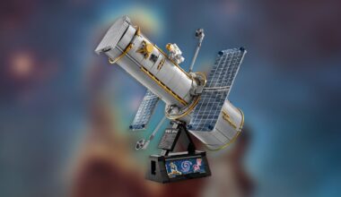 LEGO model of the Hubble Space Telescope with solar panels and mini astronaut figure, displayed on a black stand with a galaxy image, against a blurred cosmic background.