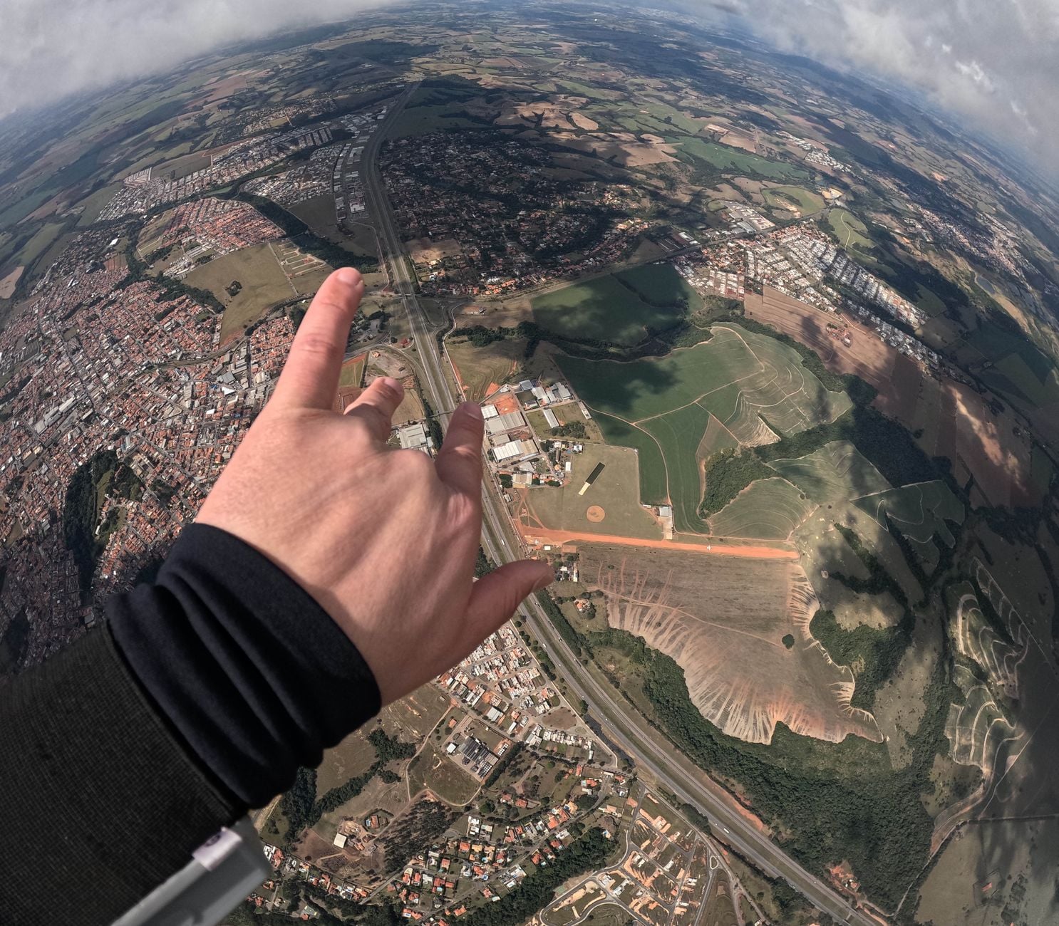 Aerial view of sprawling landscape with a hand making a gesture in the foreground.