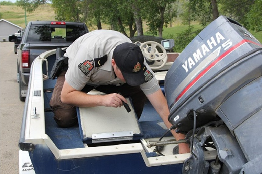 A Saskatchewan conservation officer inspects a watercraft for signs of aquatic invasive species.