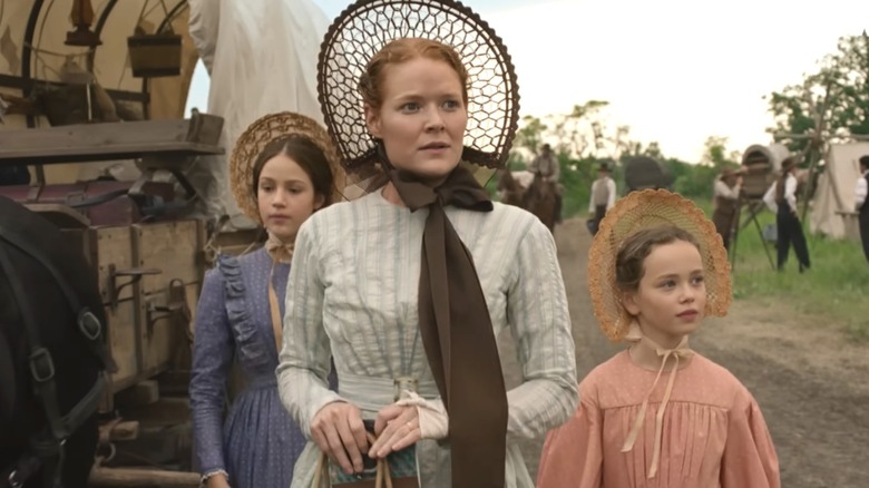 Caroline Ingalls (Crosby Fitzgerald) walks with Laura Ingalls (Alice Halsey) and Mary Ingalls (Skywalker Hughes) in Little House on the Prairie (2026)