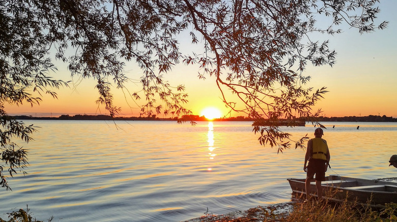 Two people and a canoe on the shore of Lake Erie at Rondeau Provincial Park, Ontario, at sunset.