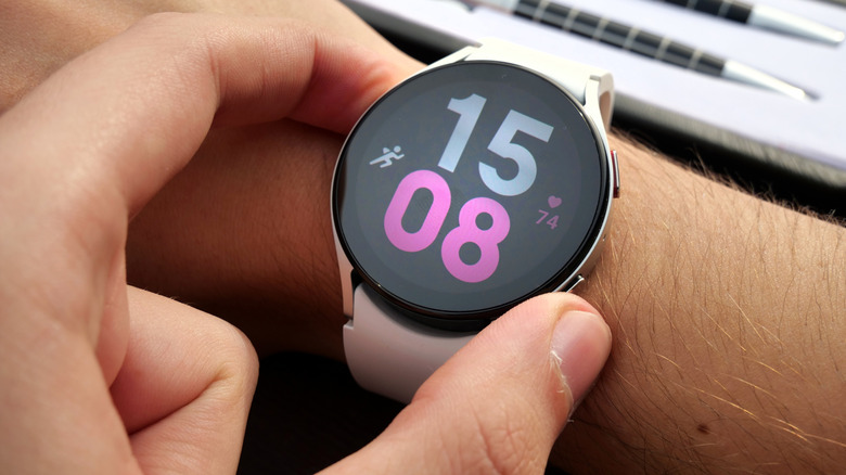 A user wearing a Samsung Galaxy Watch on their right wrist adjusts the device