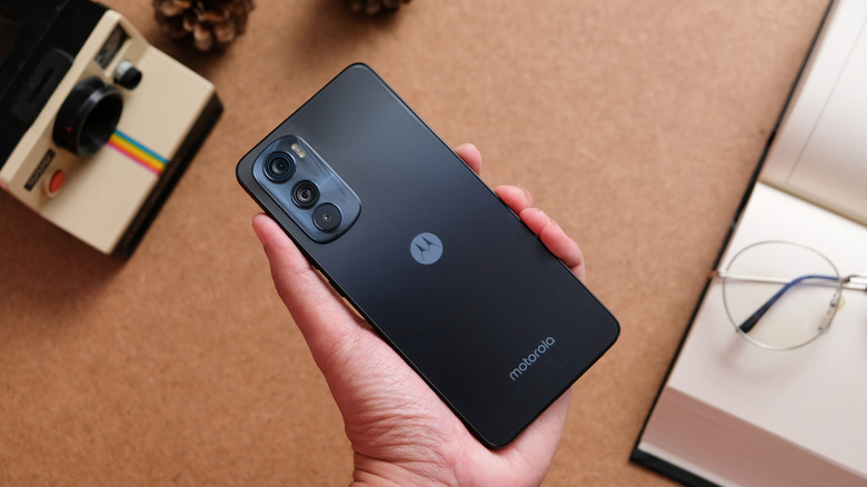 Hand holding Motorola phone upside down showing back logo and camera bump