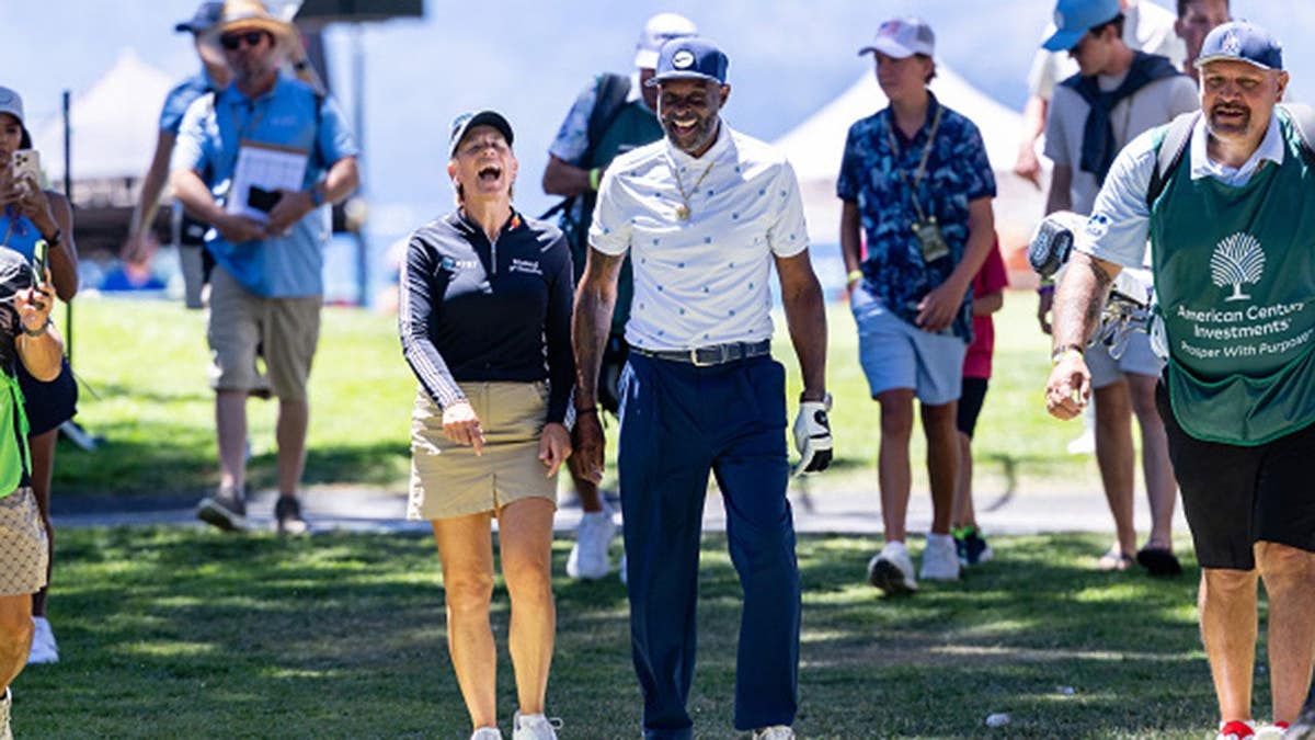 Annika Sorenstam and Jerry Rice laugh on a golf course.