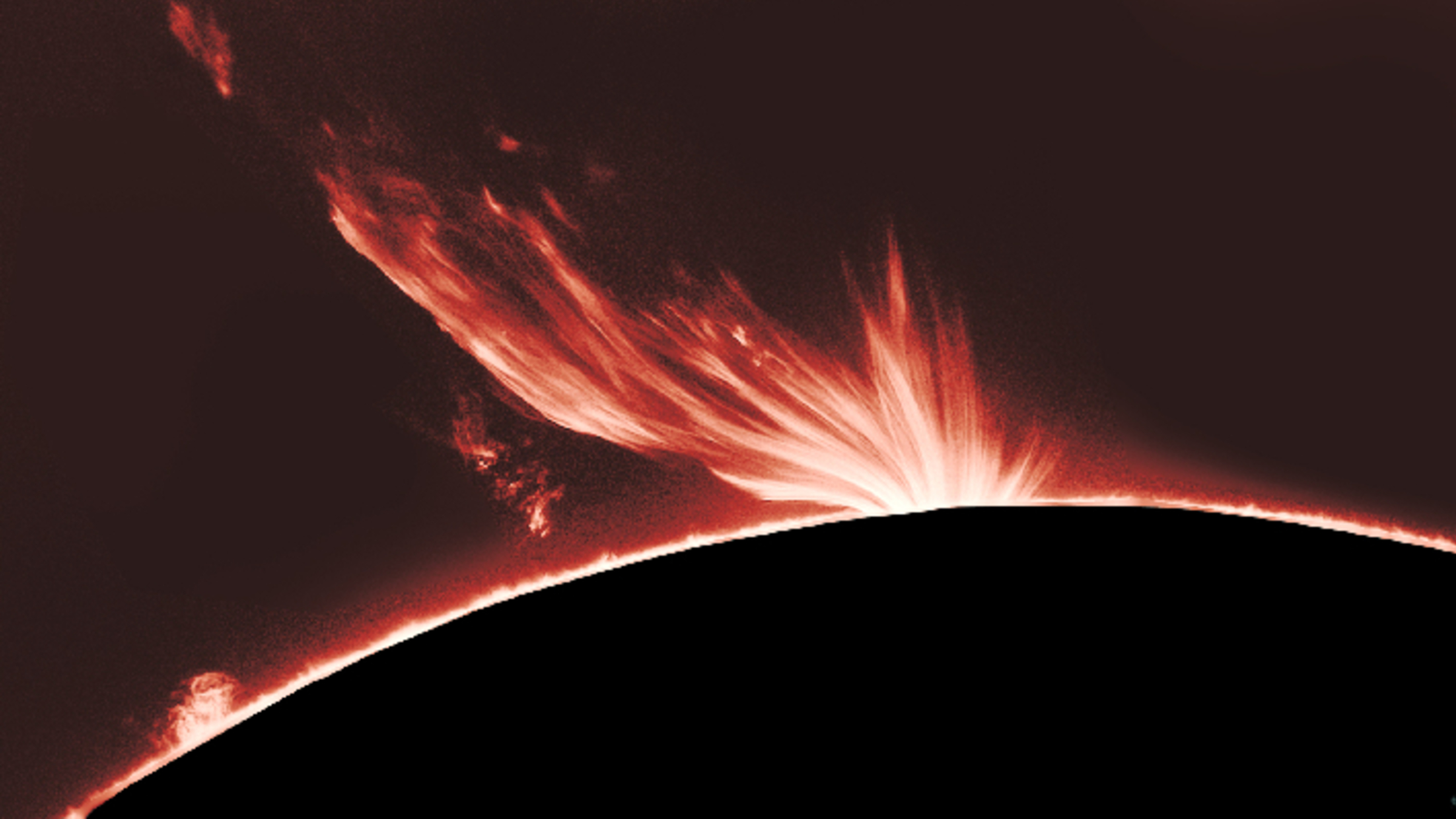 Photo of a giant red plume of plasma erupting from the sun