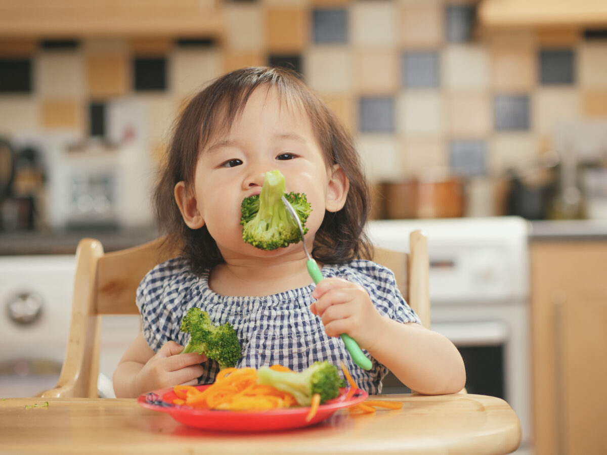 Photo shows a small child eating a large piece of broccoli at home. A new study has found that children and young people around the world are not eating enough nutritious, sustainable, plant-based foods