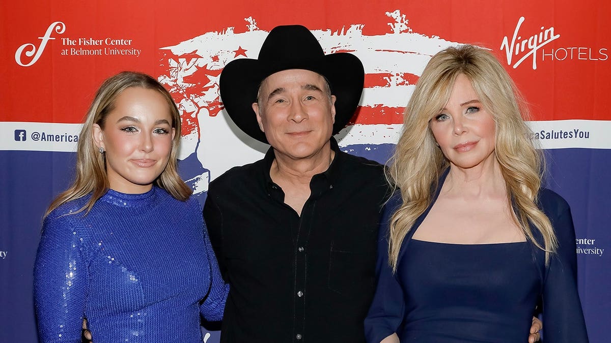 Lily Pearl Black, Clint Black and Lisa Hartman Black standing together at a concert venue.