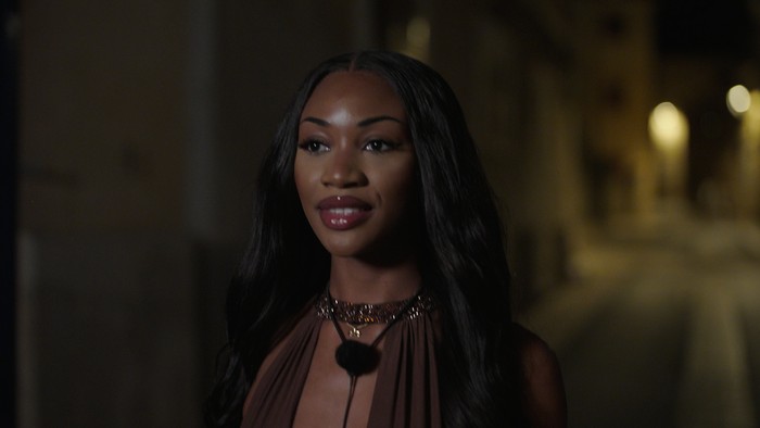 Love Island S13 A woman walking down a dimly lit road with a slight smile.