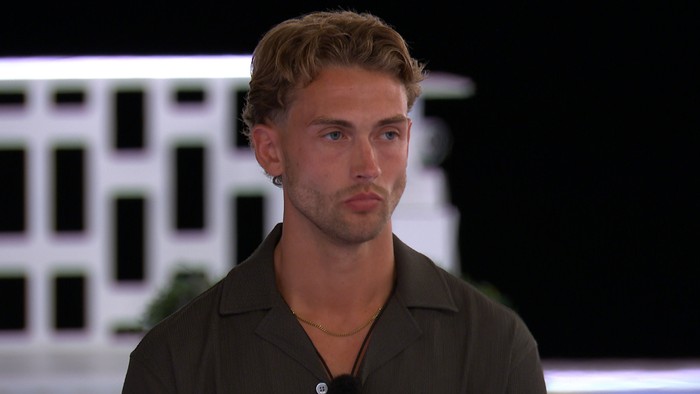 Love Island S13 A man stood at the end of the Love Island villa fire pit, looking seriously ahead.