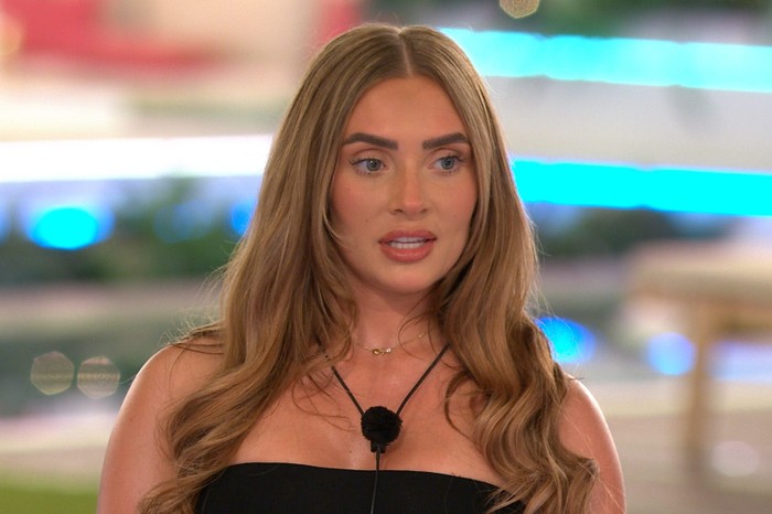 Love Island S13 Elicia looking ahead as she stands at the edge of the firepit, wearing a black bandeau top.