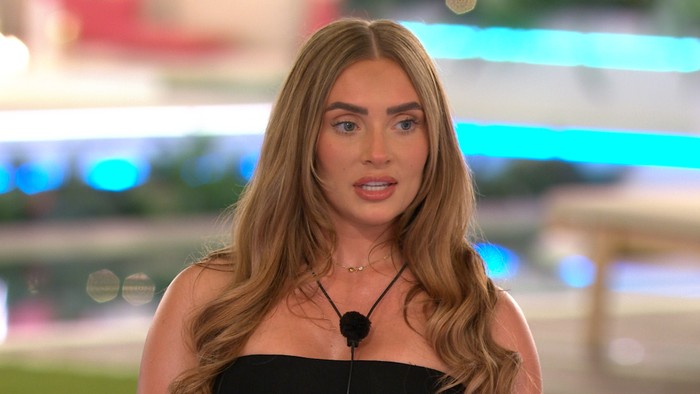 Love Island S13 Elicia looking ahead as she stands at the edge of the firepit, wearing a black bandeau top.