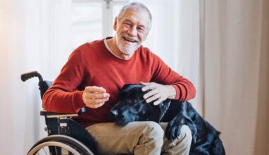 A disabled senior man in wheelchair playing with a pet dog at home.