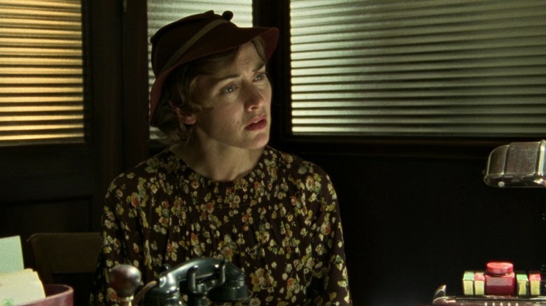 Mildred sitting before a desk with a worried expression on Mildred Pierce S1E1