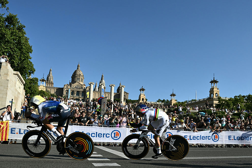Red Bull - BORA - hansgrohe team's Belgian rider Remco Evenepoel (R) cycles with his team next to the Palau nacional ('National Palace') on the hill of Montjuic during the 1st stage of the 113th edition of the Tour de France cycling race, a 19,6 km team time trial stage in and around Barcelona in northeastern Spain, on July 4, 2026. (Photo by Jeff PACHOUD / AFP)