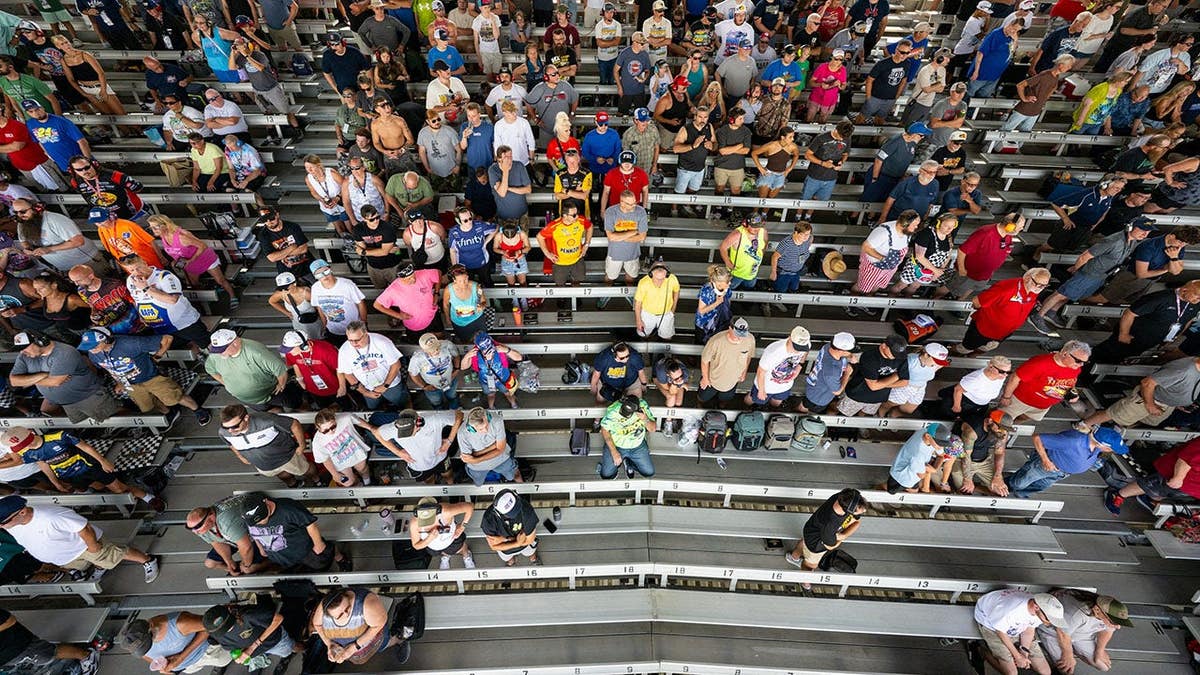 Fans stand in the grandstands at Indianapolis Motor Speedway during a NASCAR race.