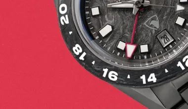 Close-up of a black watch face with white hour markers, a red-tipped second hand, and a date window showing