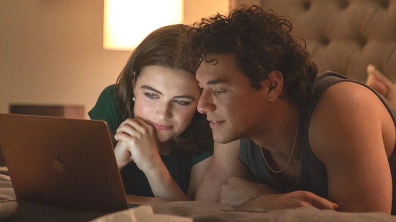 Hannah Wells and Garrett Graham laying on the bed while looking at a laptop in Off Campus