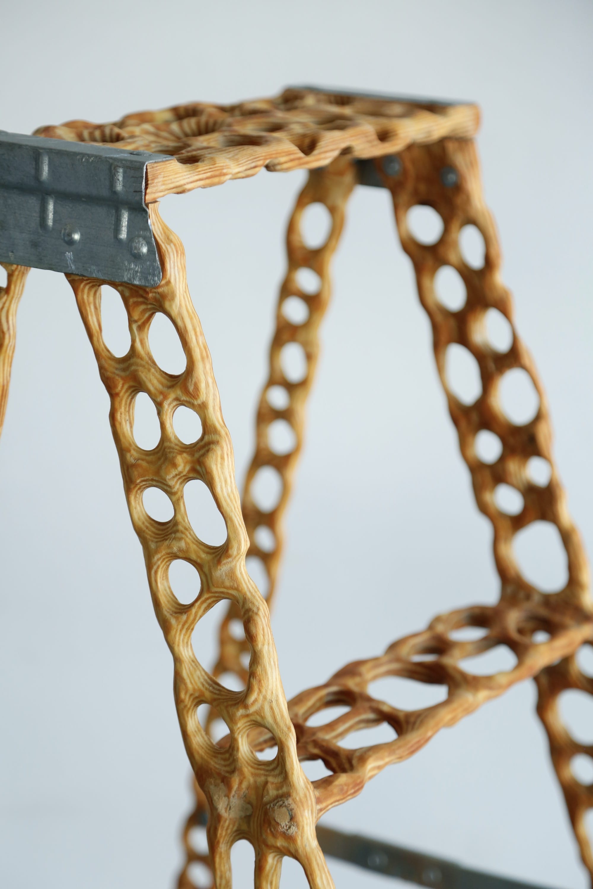 a detail image of a carved wood ladder with irregularly shaped holes