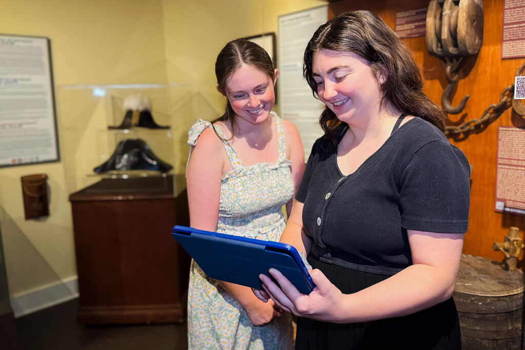 Two people looking at a tablet inside a museum.