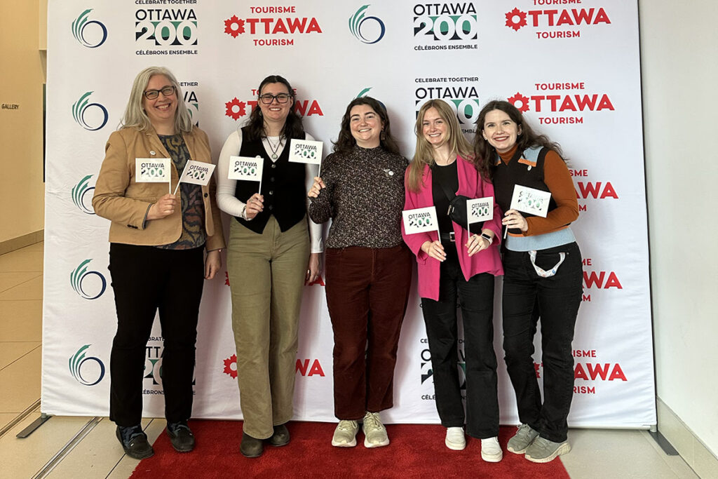 Five people posing for a group photo while holding small flags.