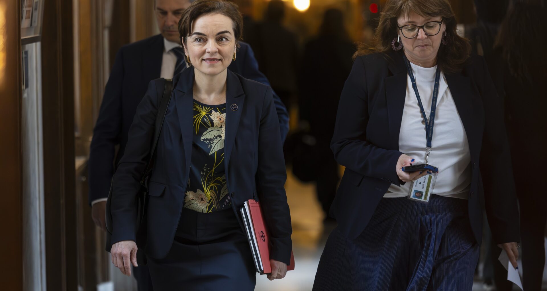 Quebec Premier Christine Fréchette walks along a National Assembly hallway with people behind her.