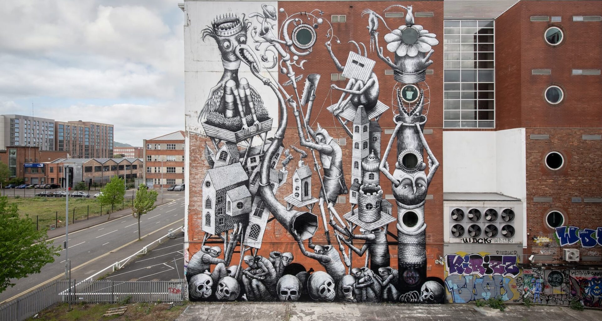 a mural by Phlegm on the side of a building featuring cartoonish figures and objects merged with lots of different shapes