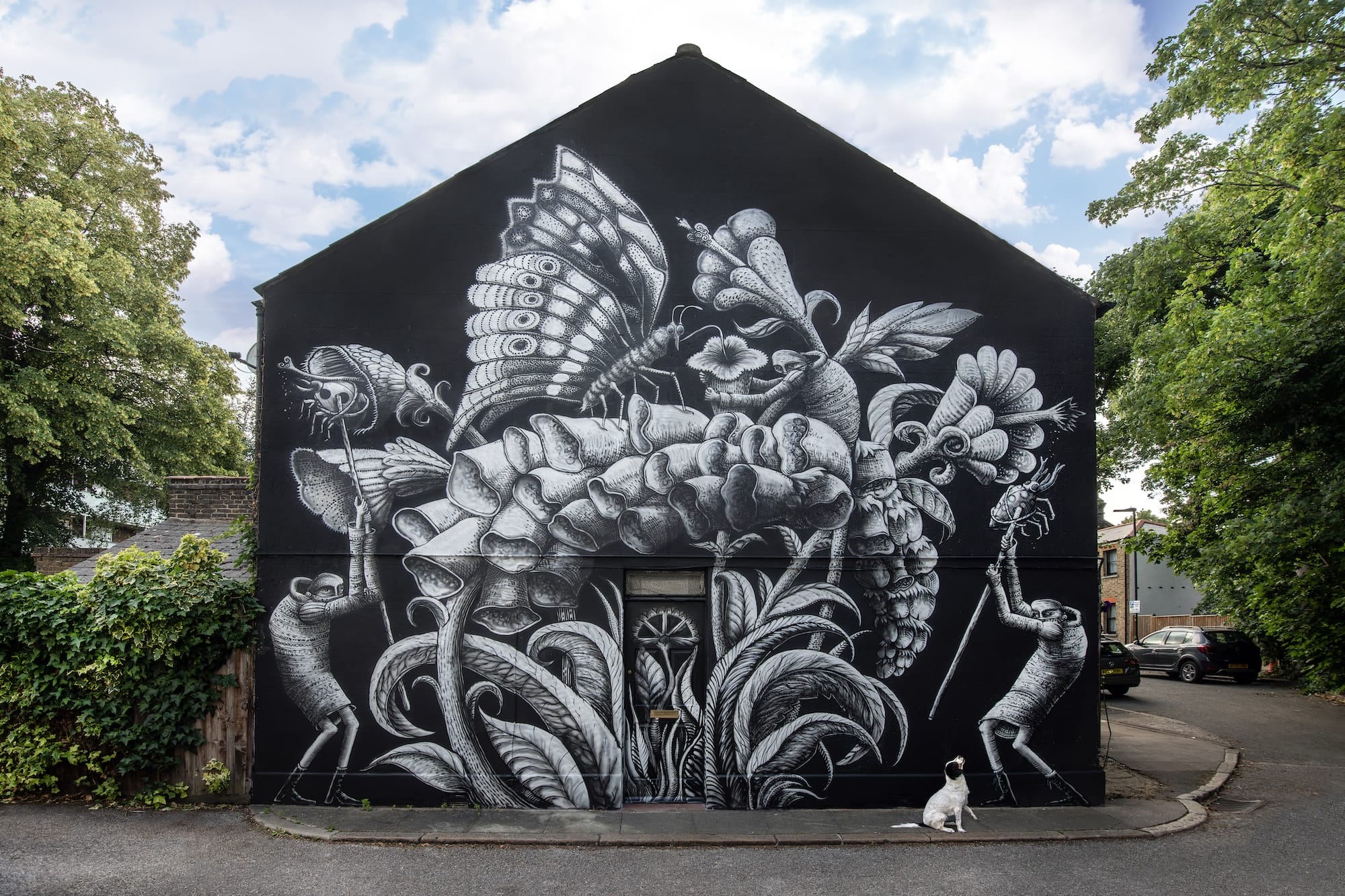 a mural by Phlegm on the side of a building featuring flowers and insects against a black background