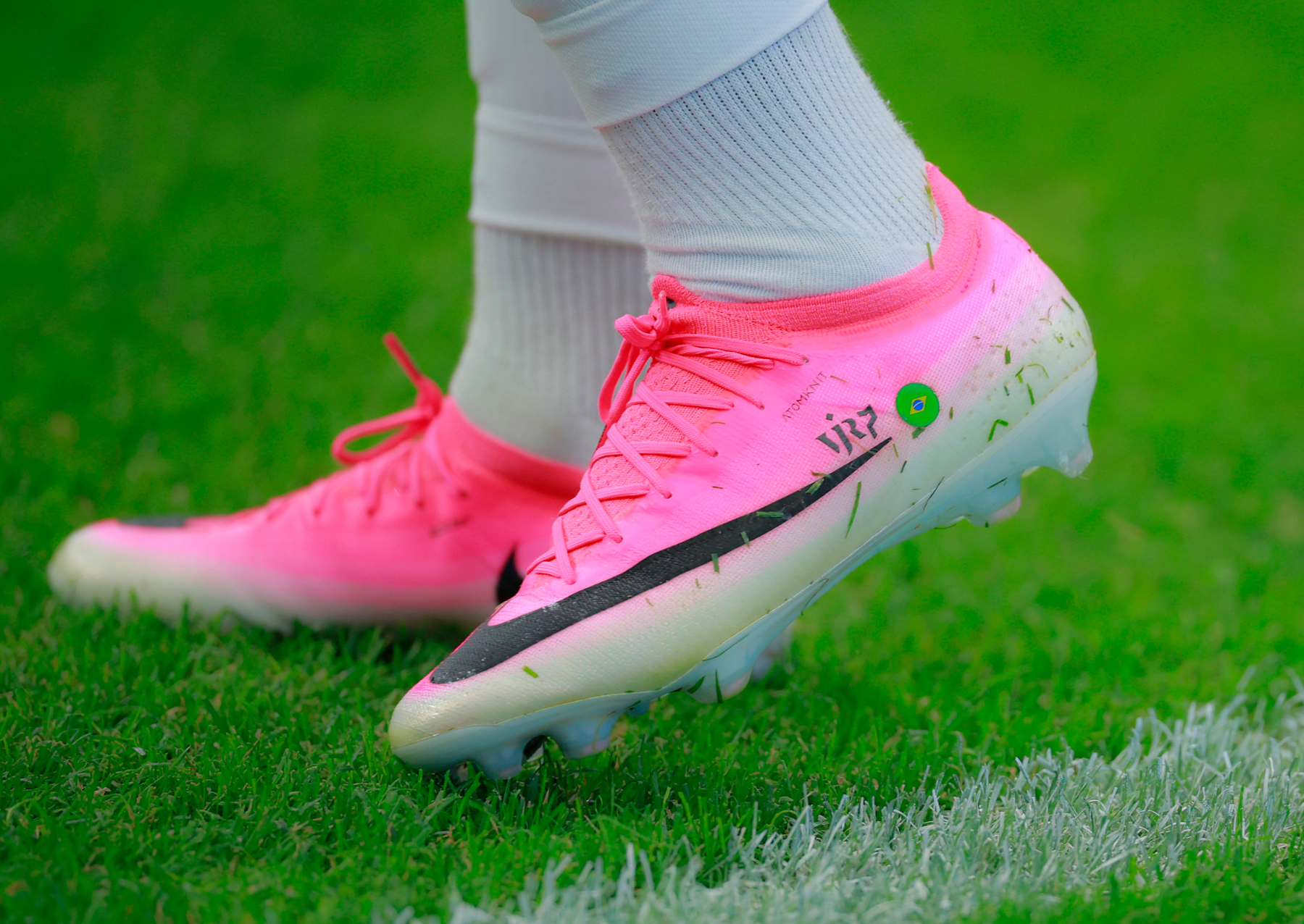 a pair of bright pink and white soccer cleats on green grass