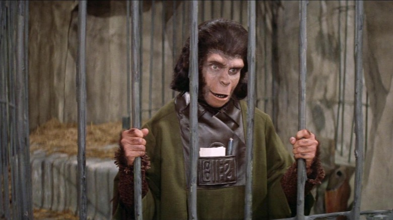 Kim Hunter as Dr. Zira in Planet of the Apes, holding on to the bars of a jail cell.