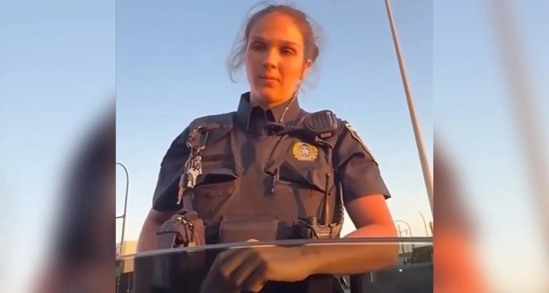 Police officer stands beside car.