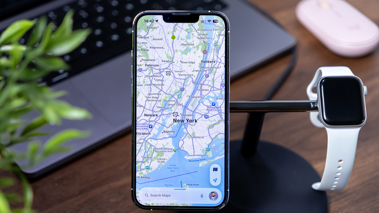 Apple Maps running on an iPhone that's on a stand beside an Apple Watch.