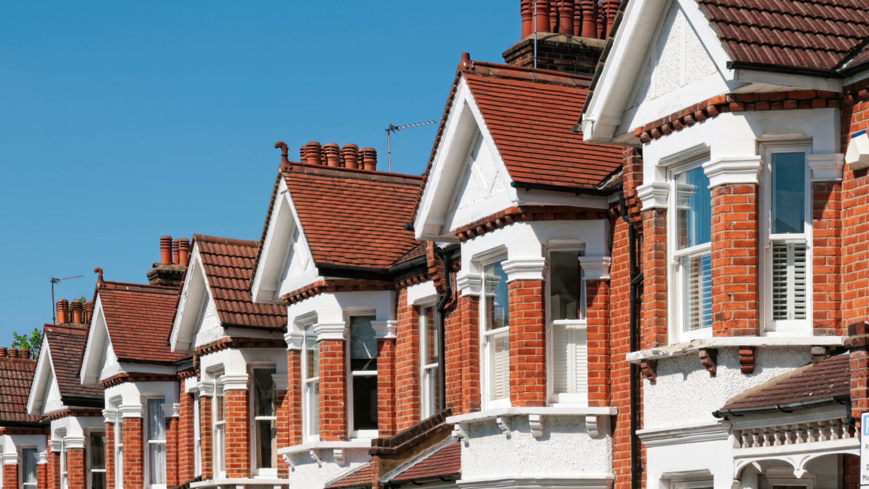 Rooftops of houses on a street with a blue sky