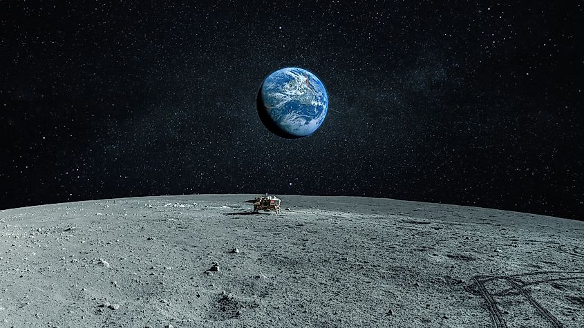 Landscape of the moon with stones and craters, blue planet earth in the background