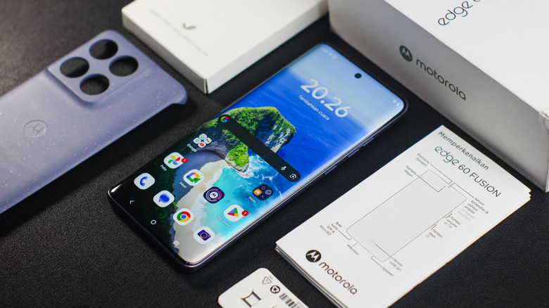 Motorola Edge Fusion laying on table with screen on next to box contents