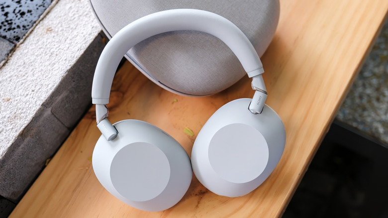 A white Sony WH-1000XM6 leaning on its cover on a wooden table