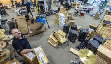 Man stands amid boxes of musical instruments in store.