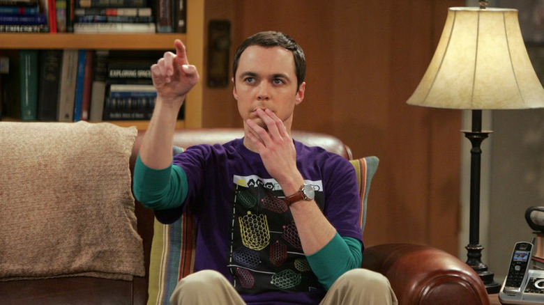 Sheldon Cooper (Jim Parsons) points while seated on a couch in The Big Bang Theory