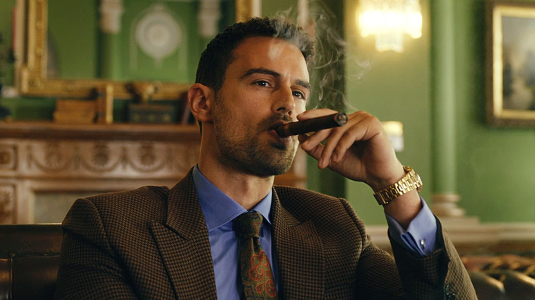 Theo James as Eddie Horniman smoking a cigar in The Gentlemen.