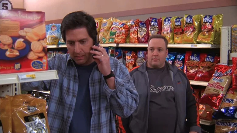 Ray Barone (Ray Romano) speaks on a cell phone in a supermarket while Doug Heffernan (Kevin James) watches in The King of Queens