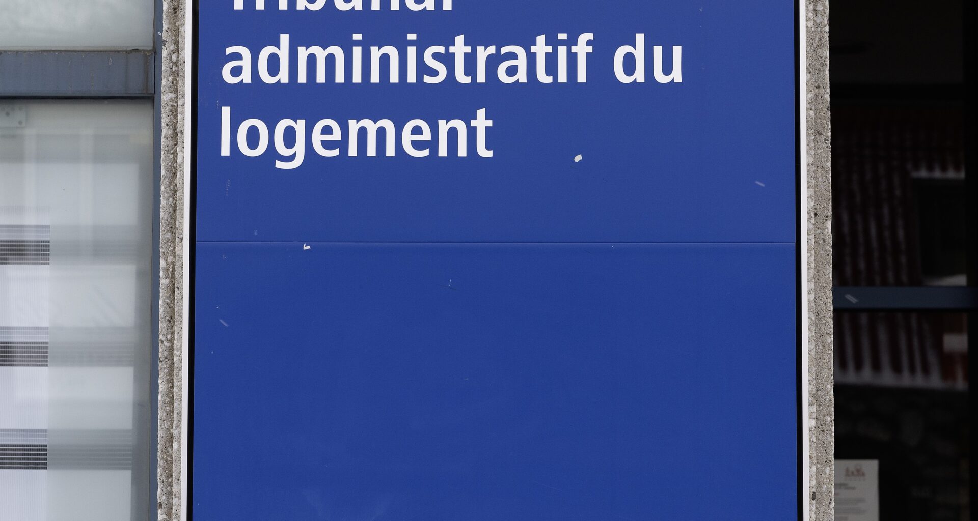 Sign for Tribunal office on building wall outside.