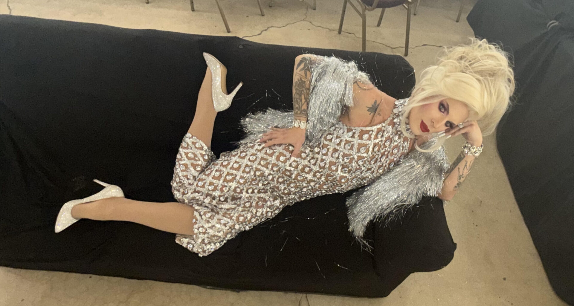 Katya Zamolodchikova reclining on a couch in a silver dress