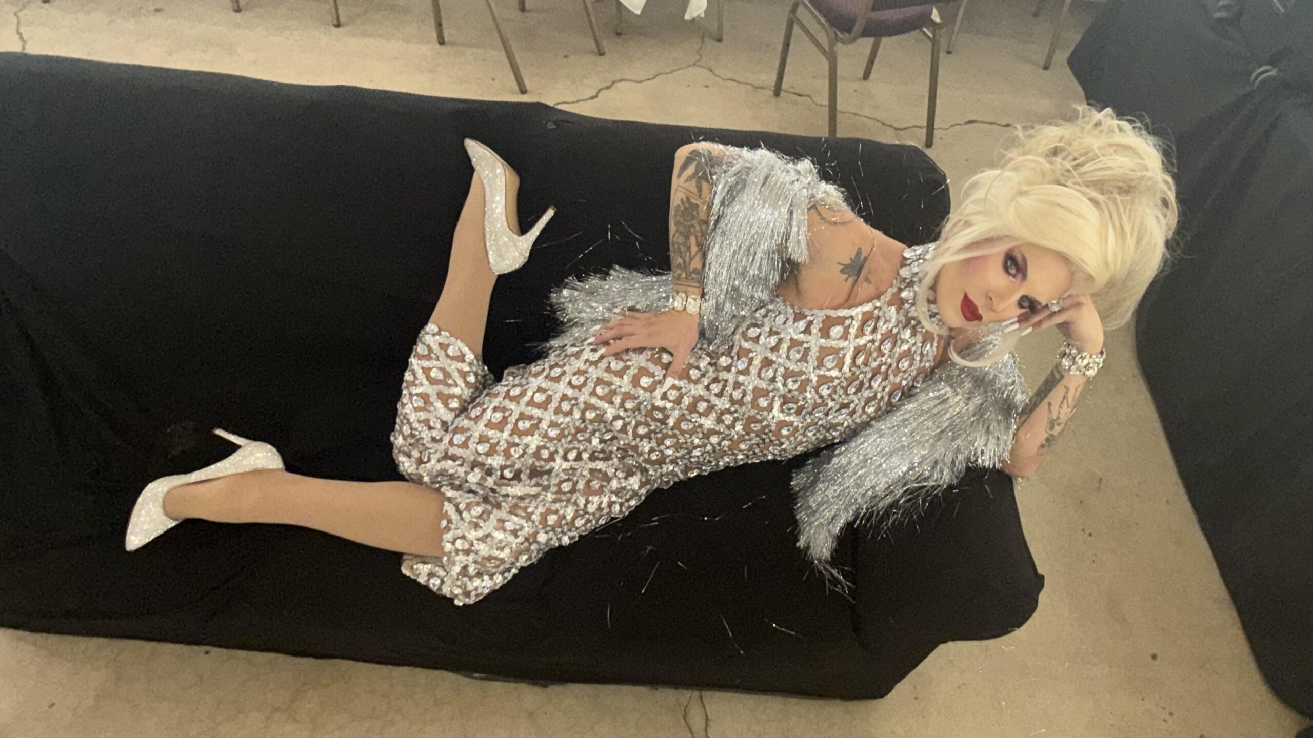 Katya Zamolodchikova reclining on a couch in a silver dress
